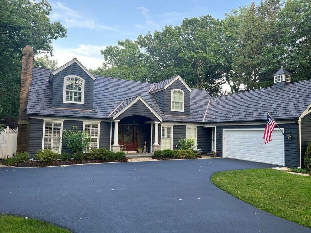 Elegant blue house with a large front yard, driveway, and American flag near the entrance.